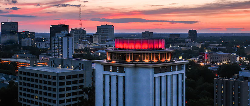 The top of Capstone lit garnet with downtown Columbia in the background