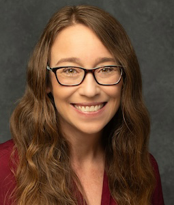 woman with glasses and garnet shirt smiling