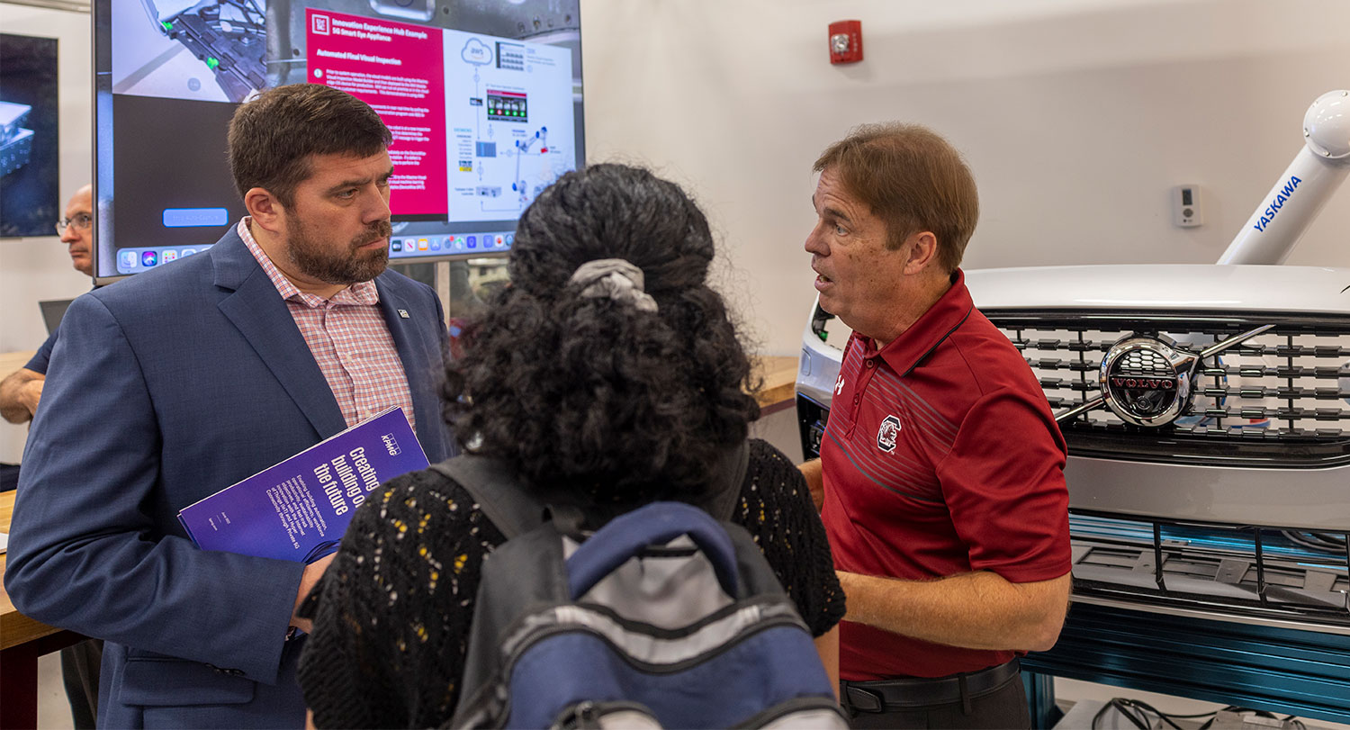 Researcher presenting to a people in front of a Volvo car front. 