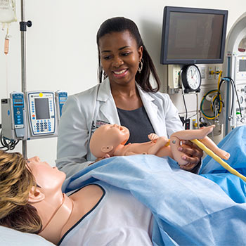 Student holding a medical practice baby with another practice patient serving as the mother. 