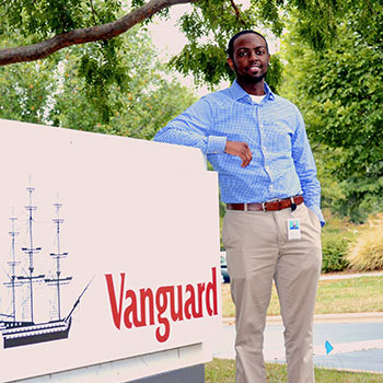 Student standing beside a Vanguard sign. 