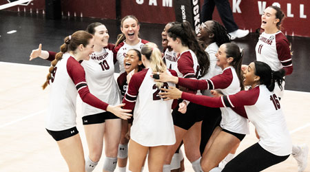 members of the volleyball team gather on the courst to celebrate a win