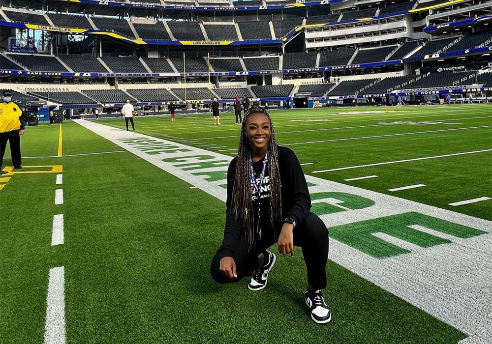 Student squatting down on an NFL football field. 