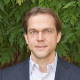 photo of a man in a blue suit jacket over a buttoned up shirt