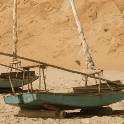 Two green sailboats pulled up on the shore.