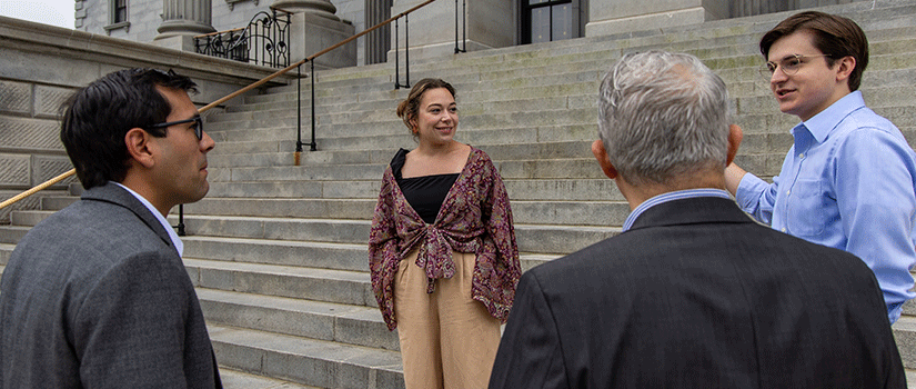 two students at the State House with faculty 