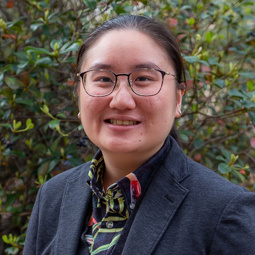 woman standing outside with glasses and blue blazer on with a colorful shirt