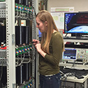 Student look at circut boards on a shelf, it illustrates a researcher working in a power and energy systems laboratory.