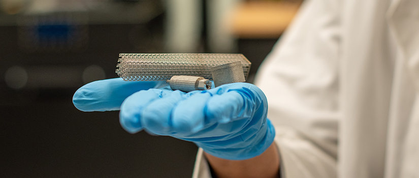 Lang Yuan holds 3D printed metal in his hand.