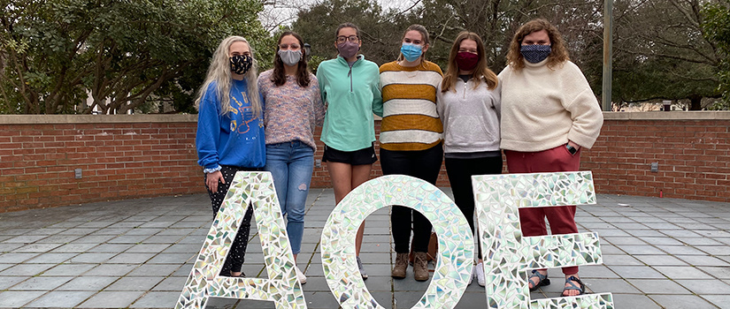 AOE's new class stands in front of the organization's greek letters.