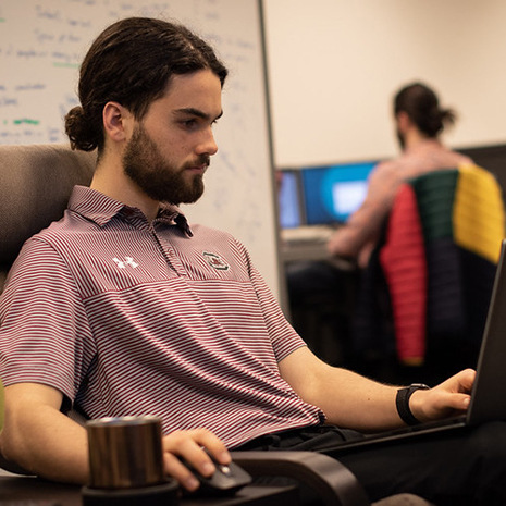 a grad student works on a laptop in a classroom