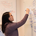 student writes on a whiteboard