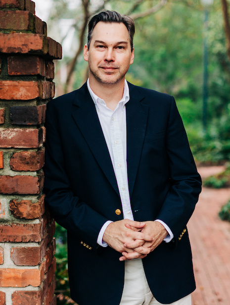 Michael Flansburgh in navy sportcoat posing for headshot on the USC Horseshoe