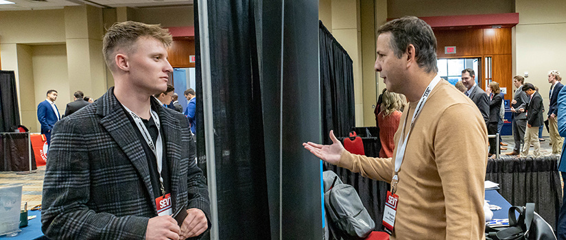 A professor speaks with a student at the Sport Entertainment and Venues Tomorrow conference.