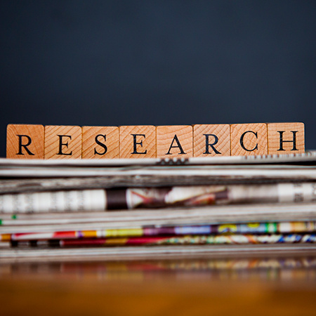 Publications stacked on a table with the word "research" on top in block letters.