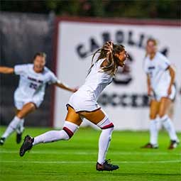 Elexa Bahr runs across the soccer field to celebrate a score with her team.