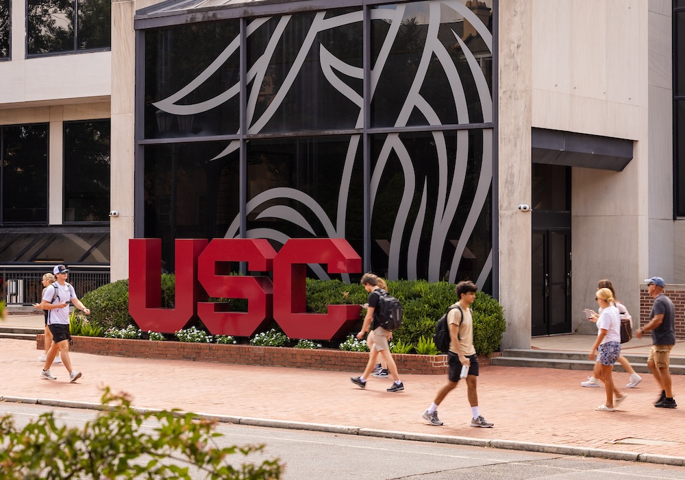 students walking past garnet USC sign