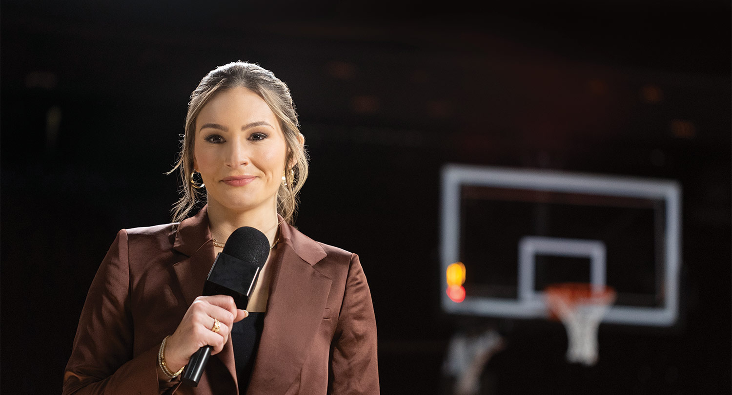 Alyssa Lang holding a microphone on basketball court