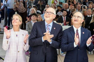 three people clap and stand in front of an audience