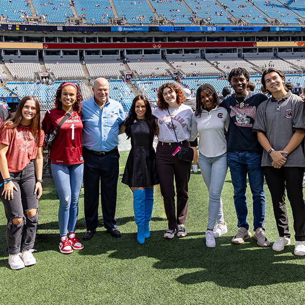 A group of students with NFL sports team owners on the Carolina Panther's stadium