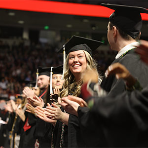 Group of students in graduation cap and gowns posing for a photo.