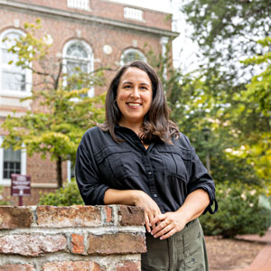 Woman in black shirt smiling against brick building with ivy