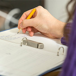 person takes notes with a pencil