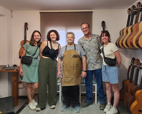 Bill Frye and three classmates pose with a Spanish luthier in a guitar shop, surrounded by flamenco guitars.