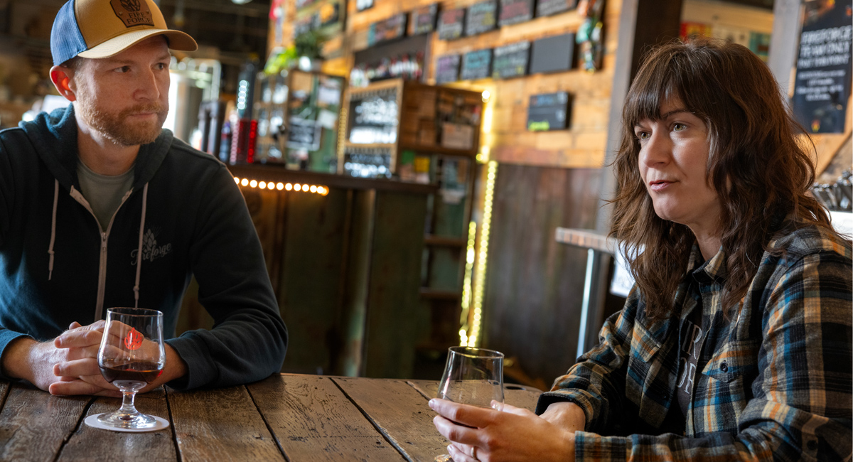 two people sit at a table with a bar in the background