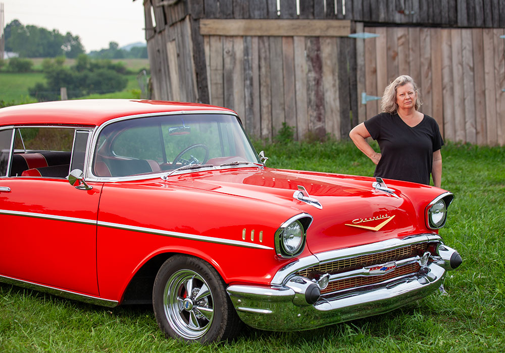 Filmmaker Ginger Cassell stands by a cherry-colored car utilized for an episode featuring cherries.